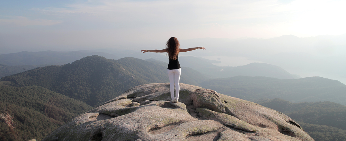 Foto de uma menina pairando a paisagem no alto do morro.